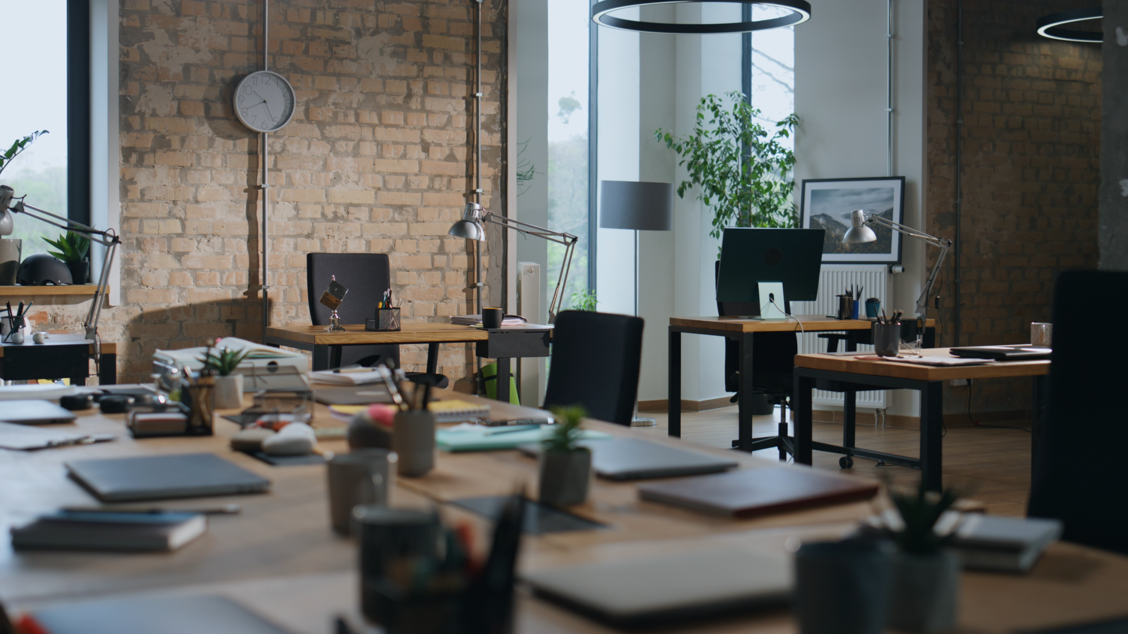 A light-filled studio with exposed brick, plants, and workspaces
