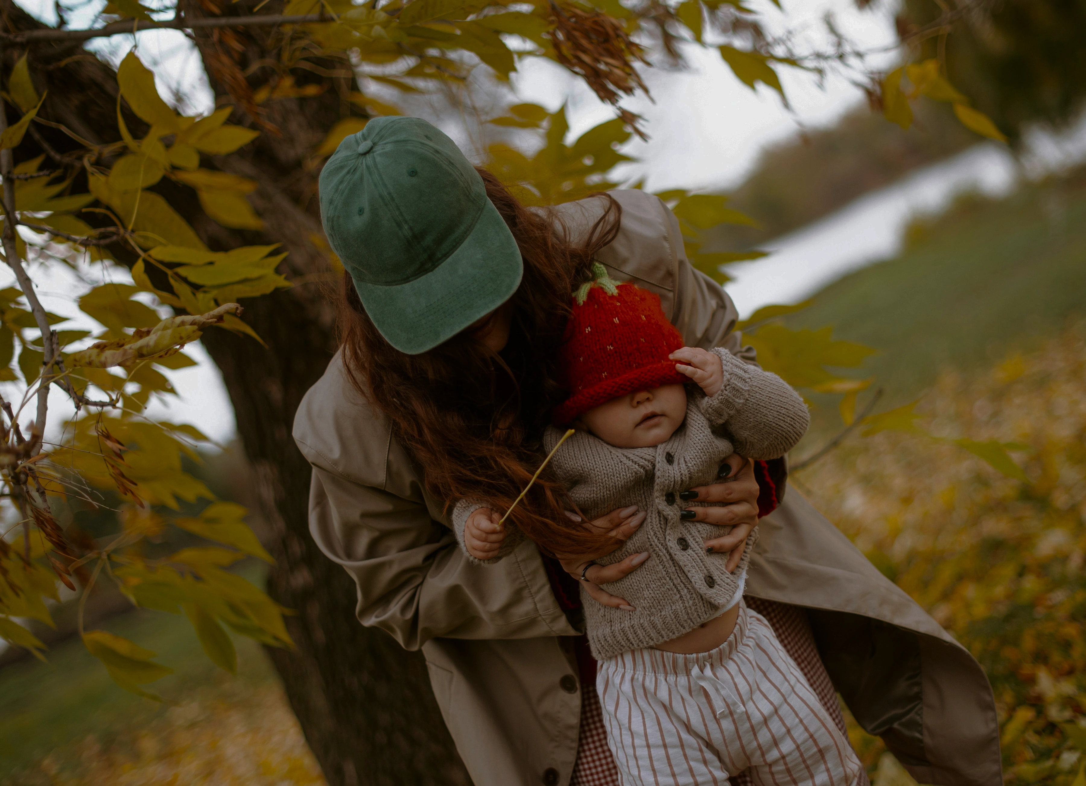 A mother holding her child among autumn leaves